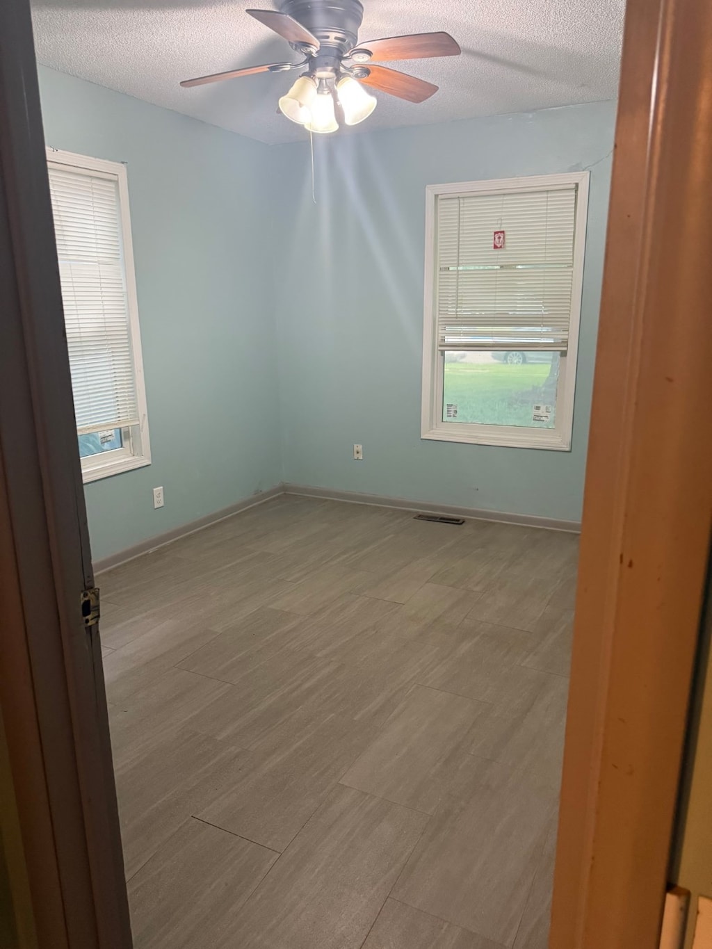 1220 Spencer St, Grinnell, IA 50112 - empty room featuring ceiling fan, a textured ceiling, and wood finished floors