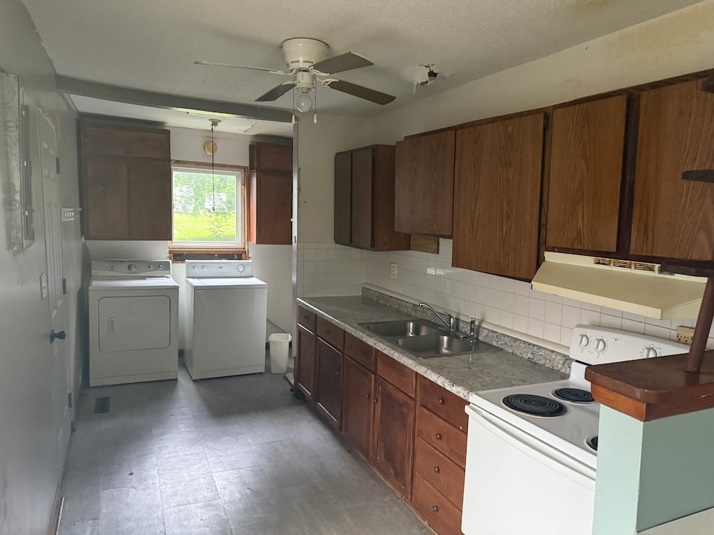 1220 Spencer St, Grinnell, IA 50112 - kitchen with white range with electric stovetop, independent washer and dryer, range hood, ceiling fan, and tasteful backsplash