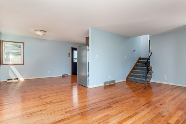 7013 Twana Dr, Urbandale, IA 50322 - unfurnished living room with light wood-style flooring and stairway