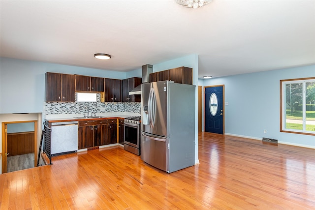 7013 Twana Dr, Urbandale, IA 50322 - kitchen with stainless steel appliances, light wood-style flooring, tasteful backsplash, dark brown cabinetry, and light countertops