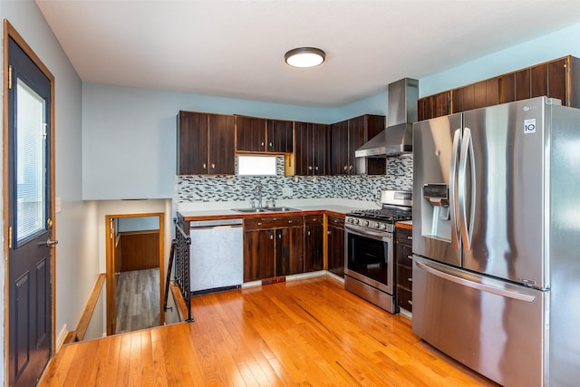 7013 Twana Dr, Urbandale, IA 50322 - kitchen featuring appliances with stainless steel finishes, wall chimney range hood, light wood-style floors, decorative backsplash, and dark brown cabinets
