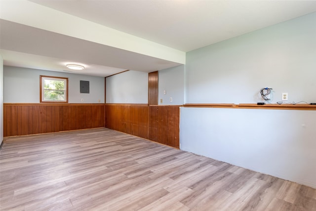 7013 Twana Dr, Urbandale, IA 50322 - spare room featuring light wood-style flooring, electric panel, a wainscoted wall, and wood walls