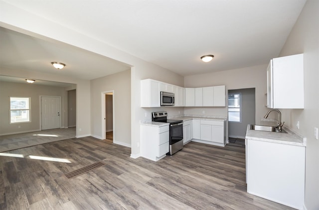 1332 E Sheridan Ave, Des Moines, IA 50316 - kitchen featuring appliances with stainless steel finishes, open floor plan, dark wood-style flooring, light countertops, and white cabinetry