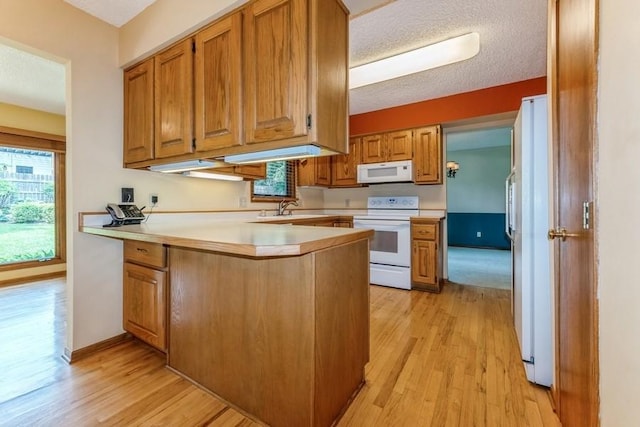 520 34th Pl, West Des Moines, IA 50265 - kitchen featuring white appliances, a peninsula, light wood-type flooring, light countertops, and a textured ceiling