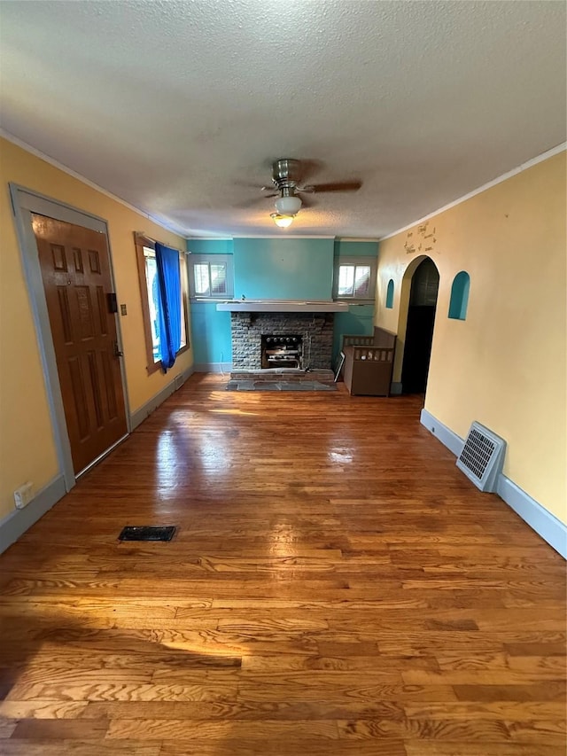 208 E 16th St, Des Moines, IA 50316 - unfurnished living room with ornamental molding, a ceiling fan, a brick fireplace, wood finished floors, and a textured ceiling
