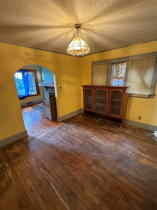 208 E 16th St, Des Moines, IA 50316 - unfurnished dining area with arched walkways, a chandelier, a textured ceiling, wood finished floors, and crown molding