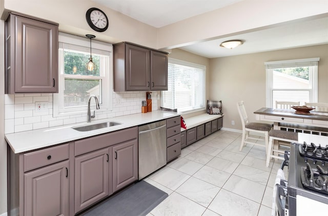 1808 60th St, Des Moines, IA 50322 - kitchen featuring stainless steel dishwasher, decorative backsplash, stove, light countertops, and hanging light fixtures