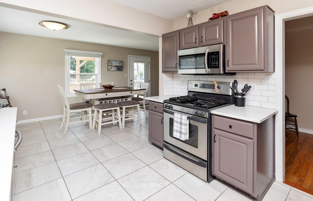 1808 60th St, Des Moines, IA 50322 - kitchen featuring stainless steel appliances, gray cabinetry, light countertops, and backsplash