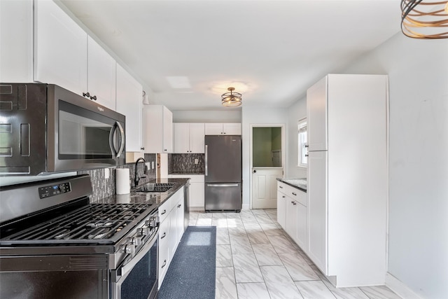 1329 63rd St, Des Moines, IA 50311 - kitchen featuring stainless steel appliances, light marble finish flooring, white cabinets, dark stone countertops, and backsplash