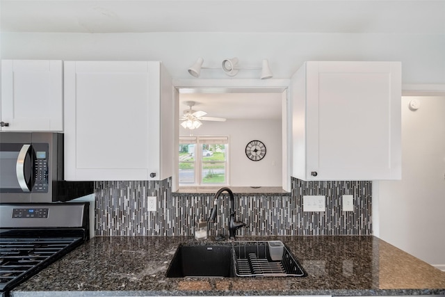 1329 63rd St, Des Moines, IA 50311 - kitchen featuring stainless steel appliances, ceiling fan, white cabinets, backsplash, and dark stone countertops