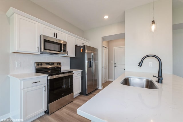 7000 Lake Hill Dr Unit 74, Des Moines, IA 50320 - kitchen with stainless steel appliances, light wood-style flooring, tasteful backsplash, white cabinetry, and decorative light fixtures