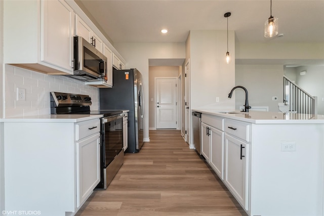 7000 Lake Hill Dr Unit 74, Des Moines, IA 50320 - kitchen featuring appliances with stainless steel finishes, white cabinetry, recessed lighting, light wood finished floors, and tasteful backsplash