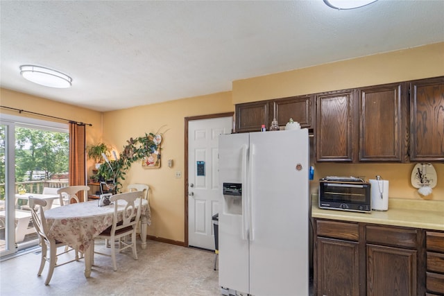 516 Walnut St, De Soto, IA 50069 - kitchen featuring white refrigerator with ice dispenser, light countertops, and dark brown cabinetry