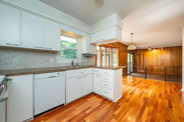 1005 32nd St, West Des Moines, IA 50266 - kitchen featuring white dishwasher, a peninsula, light wood finished floors, wooden walls, and tasteful backsplash