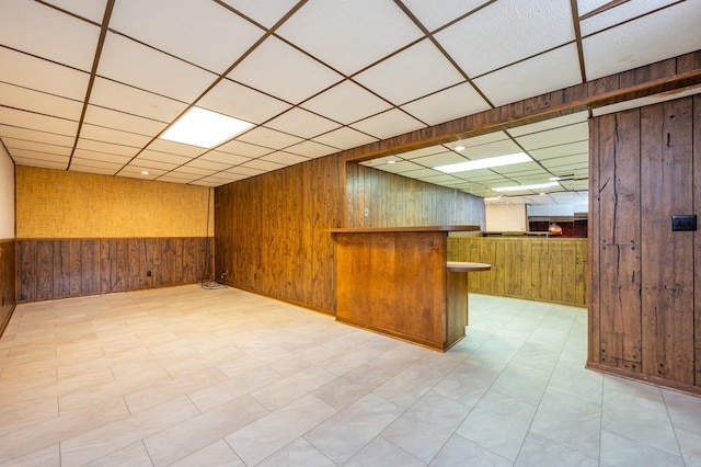 1005 32nd St, West Des Moines, IA 50266 - finished basement with wood walls, a drop ceiling, a dry bar, and light flooring