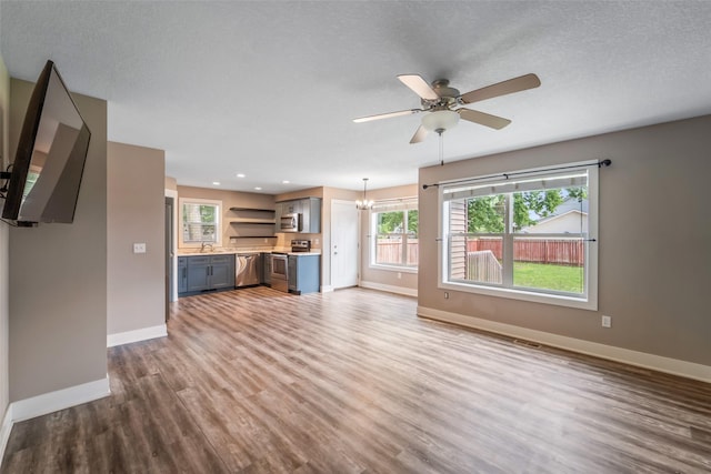 611 Court St, Adel, IA 50003 - unfurnished living room featuring healthy amount of natural light, wood finished floors, a ceiling fan, recessed lighting, and a chandelier