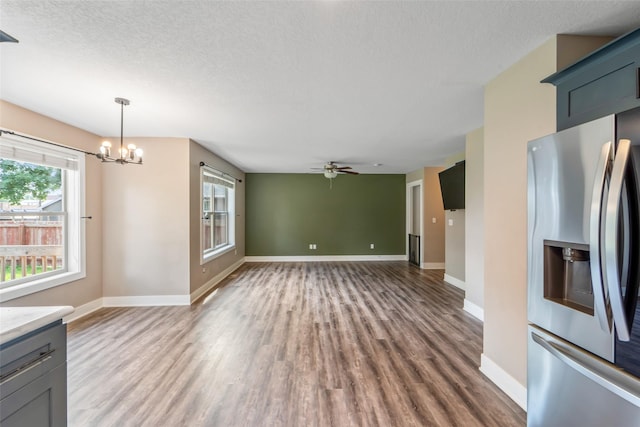 611 Court St, Adel, IA 50003 - unfurnished living room with wood finished floors, a chandelier, a ceiling fan, and a textured ceiling