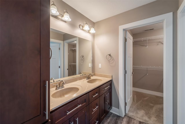 611 Court St, Adel, IA 50003 - bathroom featuring double vanity, a walk in closet, and wood finished floors