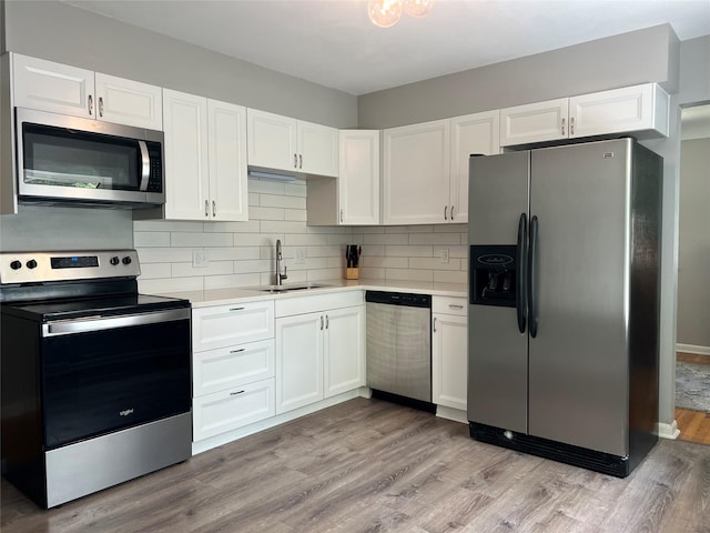 4301 43rd St, Des Moines, IA 50310 - kitchen with stainless steel appliances, light countertops, white cabinets, backsplash, and light wood finished floors