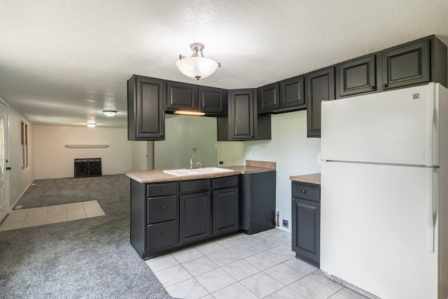 6730 NW Timberline Dr, Des Moines, IA 50313 - kitchen featuring freestanding refrigerator, light carpet, a fireplace, light tile patterned floors, and a textured ceiling