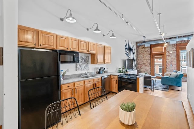 507 E Locust St Unit 308, Des Moines, IA 50309 - kitchen with black appliances, brick wall, light wood-style flooring, light countertops, and open floor plan