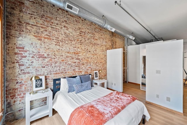507 E Locust St Unit 308, Des Moines, IA 50309 - bedroom with wood finished floors, a towering ceiling, brick wall, and rail lighting
