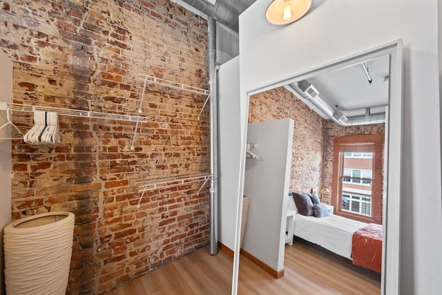 507 E Locust St Unit 308, Des Moines, IA 50309 - bathroom featuring wood finished floors, brick wall, and ensuite bathroom