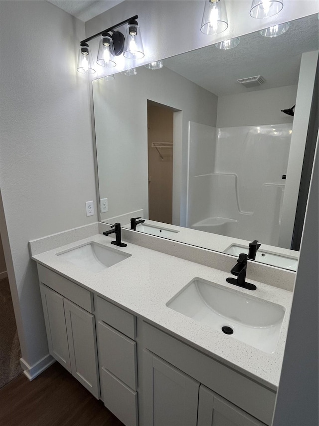 711 W N Ave, Norwalk, IA 50211 - full bathroom featuring wood finished floors, double vanity, and a shower