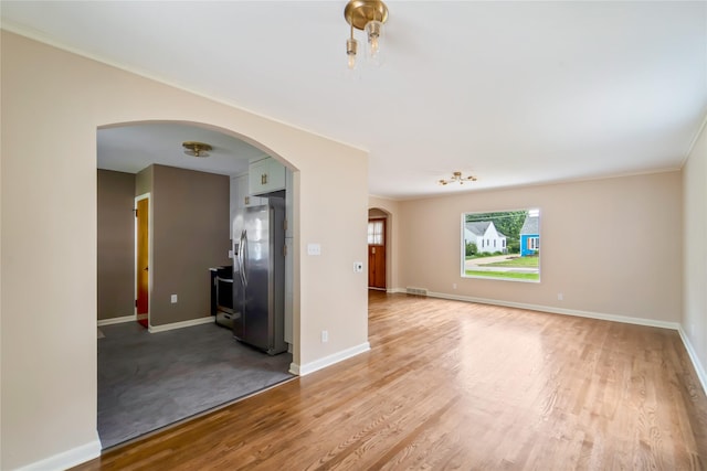 1918 55th St, Des Moines, IA 50310 - unfurnished living room with arched walkways, light wood-type flooring, and ornamental molding