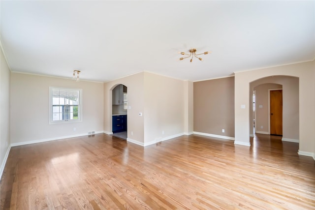 1918 55th St, Des Moines, IA 50310 - unfurnished living room featuring arched walkways, crown molding, light wood-style floors, and a chandelier