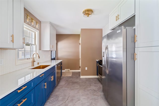 1918 55th St, Des Moines, IA 50310 - kitchen featuring appliances with stainless steel finishes, white cabinetry, blue cabinetry, light countertops, and tasteful backsplash