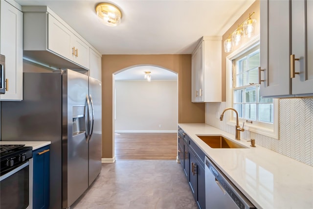 1918 55th St, Des Moines, IA 50310 - kitchen with stainless steel appliances, arched walkways, blue cabinets, light countertops, and light floors