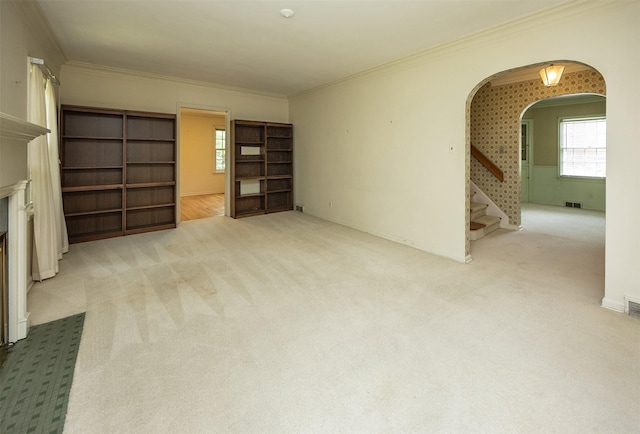 5800 Pleasant Dr, Des Moines, IA 50312 - unfurnished living room featuring arched walkways, stairway, a fireplace with flush hearth, carpet flooring, and ornamental molding