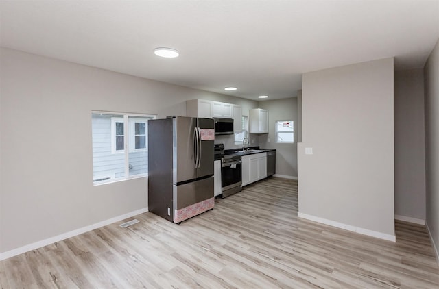 3308 Cambridge St, Des Moines, IA 50313 - kitchen featuring appliances with stainless steel finishes, white cabinets, light wood-style flooring, dark countertops, and recessed lighting
