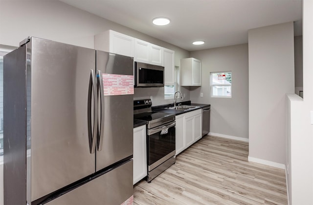 3308 Cambridge St, Des Moines, IA 50313 - kitchen with stainless steel appliances, dark countertops, white cabinetry, and light wood-style floors