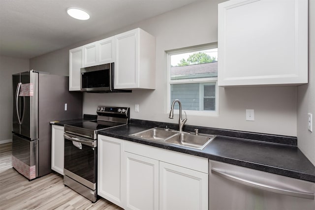 3308 Cambridge St, Des Moines, IA 50313 - kitchen with appliances with stainless steel finishes, white cabinets, dark countertops, and light wood-style flooring