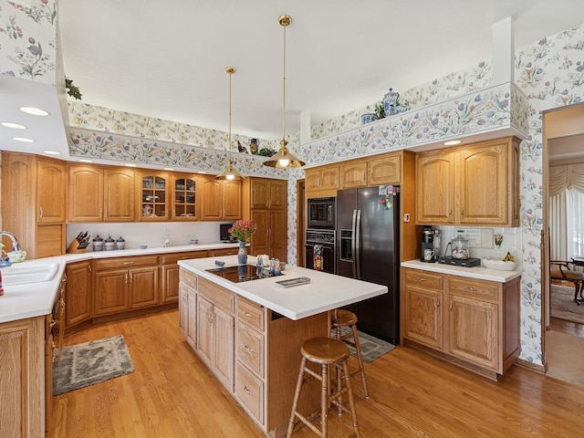 501 S 33rd St, West Des Moines, IA 50265 - kitchen with wallpapered walls, black appliances, light wood finished floors, a center island, and glass insert cabinets