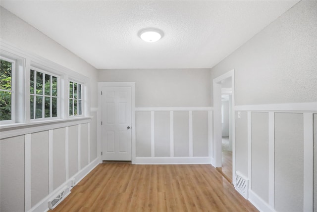 1418 33rd St, Des Moines, IA 50311 - unfurnished room with a decorative wall, wood finished floors, a textured ceiling, and wainscoting