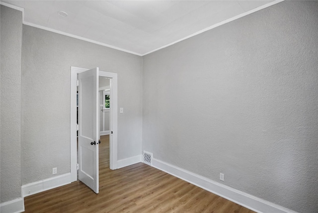 1418 33rd St, Des Moines, IA 50311 - empty room with wood finished floors, ornamental molding, and a textured wall