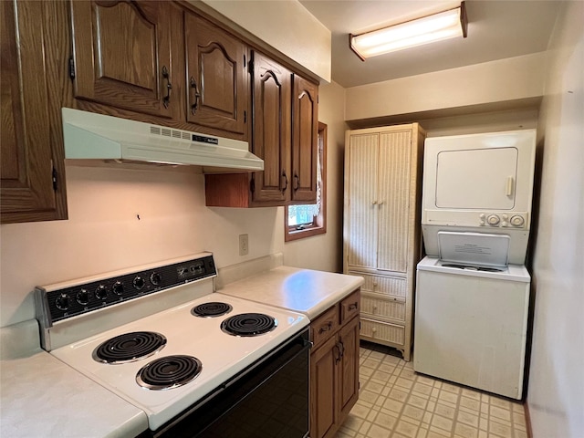 702 W 6th St S, Newton, IA 50208 - kitchen with electric stove, under cabinet range hood, stacked washing machine and dryer, light countertops, and dark brown cabinetry