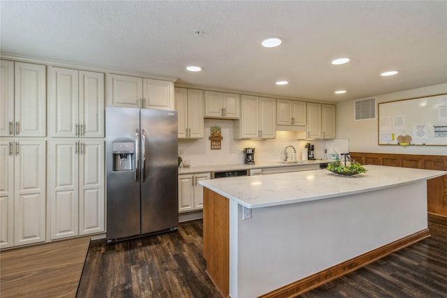 1250 SW Magazine Rd Unit 215, Ankeny, IA 50023 - kitchen with stainless steel refrigerator with ice dispenser, dark wood-type flooring, light stone counters, a kitchen island, and recessed lighting