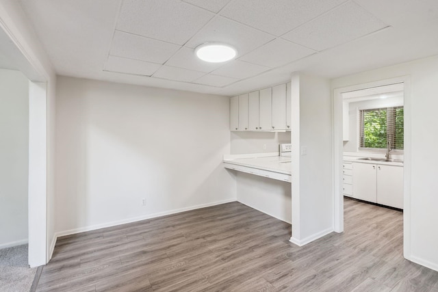 1808 80th St, Windsor Heights, IA 50324 - kitchen with light countertops, white cabinetry, wood finished floors, and a paneled ceiling
