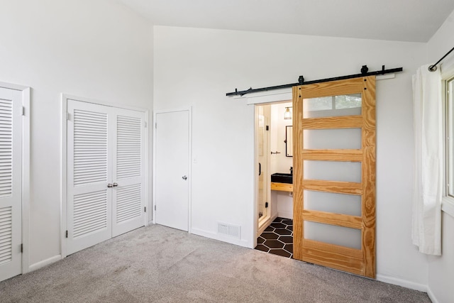 1808 80th St, Windsor Heights, IA 50324 - unfurnished bedroom featuring vaulted ceiling, a barn door, and carpet