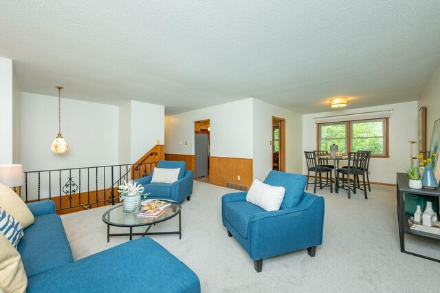 108 56th St, Des Moines, IA 50312 - living room with a textured ceiling, carpet flooring, wooden walls, and wainscoting