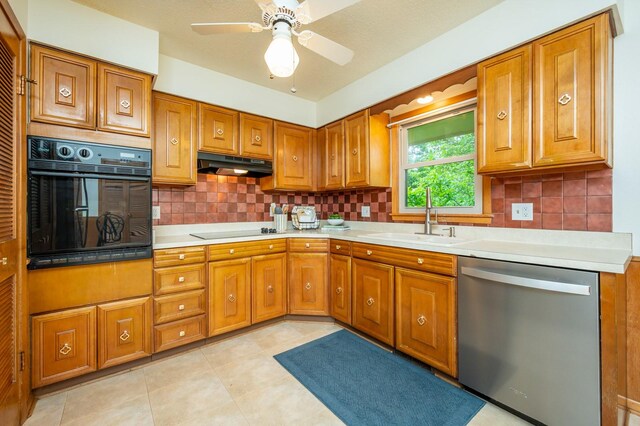 108 56th St, Des Moines, IA 50312 - kitchen featuring black appliances, under cabinet range hood, brown cabinets, light countertops, and decorative backsplash