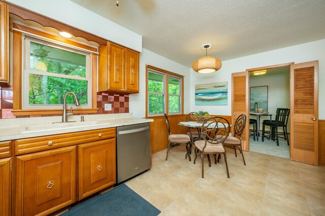 108 56th St, Des Moines, IA 50312 - kitchen featuring dishwasher, light countertops, brown cabinets, decorative light fixtures, and a textured ceiling