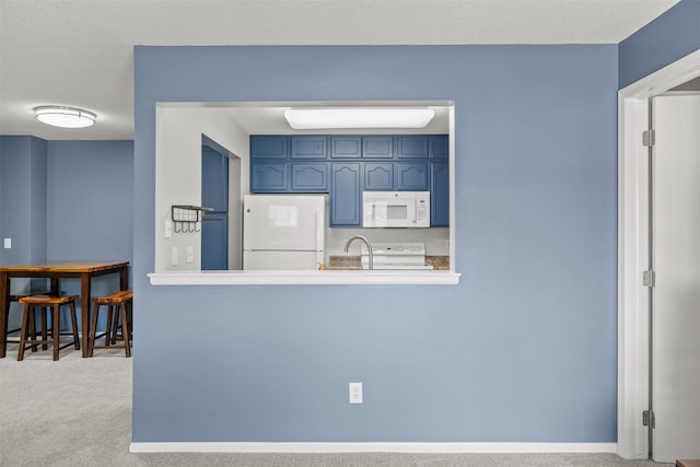 2128 NW 156th St Unit 31, Clive, IA 50325 - kitchen with white appliances, blue cabinetry, carpet, and light countertops