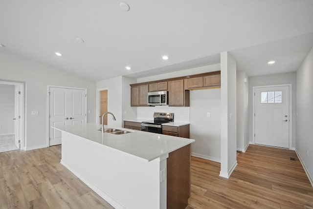 1819 Tuscany Dr SE, Altoona, IA 50009 - kitchen with stainless steel appliances, light wood-type flooring, backsplash, a kitchen island with sink, and light countertops