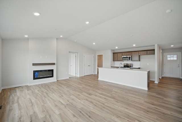 1819 Tuscany Dr SE, Altoona, IA 50009 - unfurnished living room with vaulted ceiling, recessed lighting, light wood-type flooring, and a glass covered fireplace