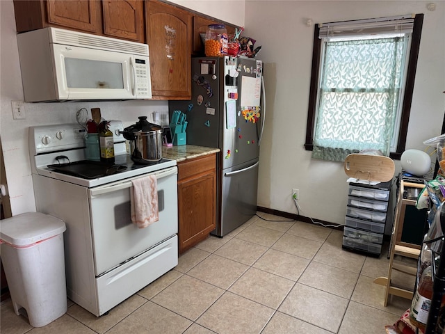 1105 Bundy St, Des Moines, IA 50315 - kitchen with white appliances, brown cabinetry, light tile patterned floors, and light countertops